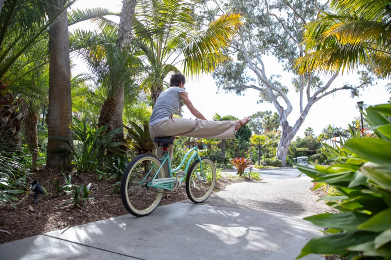 carefree woman riding bike down path at resort benefits of wellness tourism and transformation